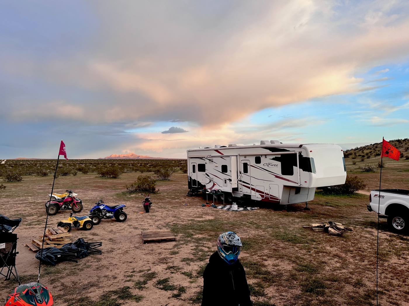 Large RV with dirt bikes parked in the open desert at dusk